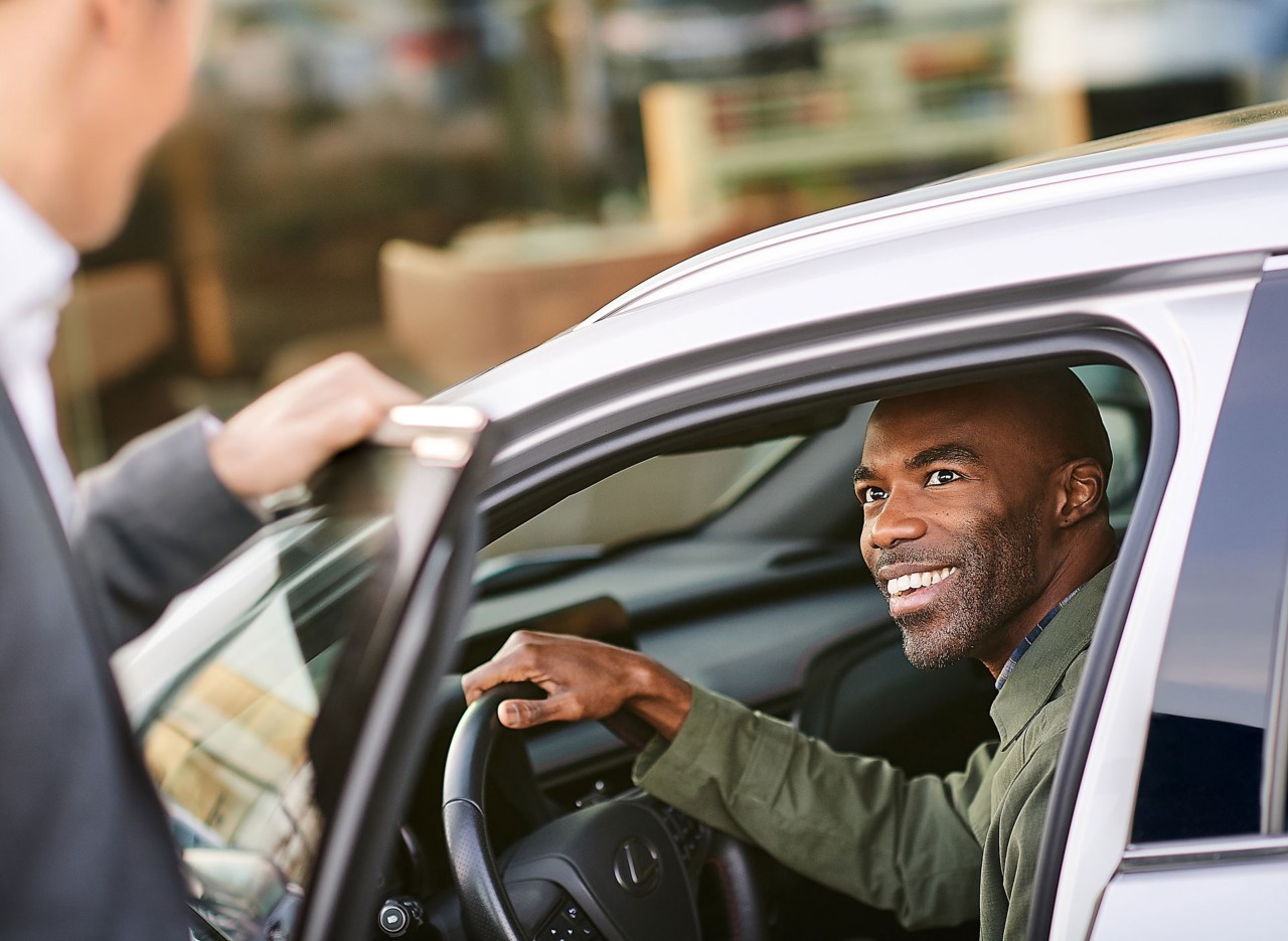 A person smiling in the driver's seat of a Lexus, enjoying Lexus Business Renting.