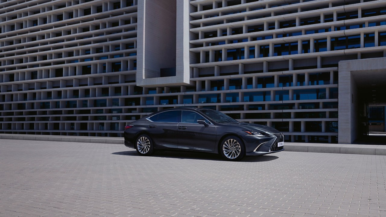 A man walking towards a parked Lexus ES