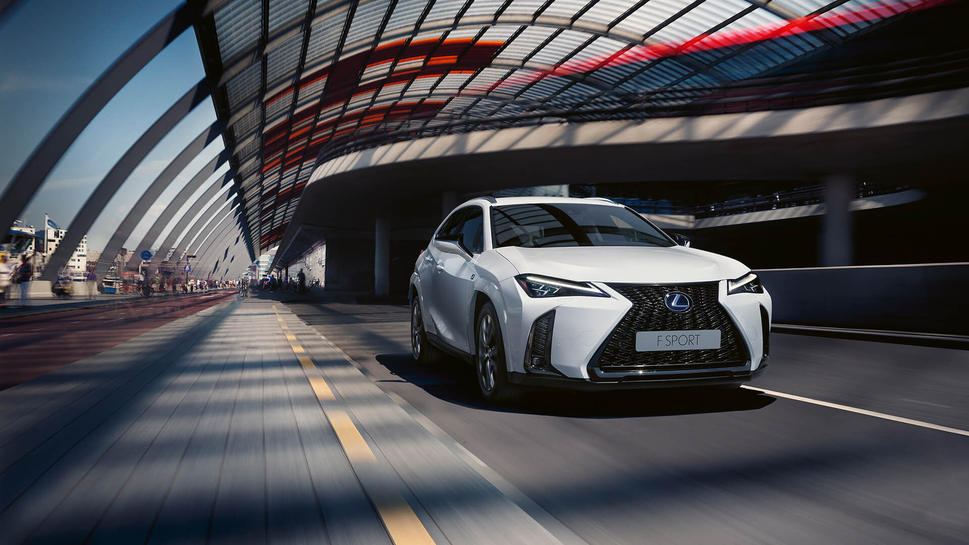 A Lexus UX driving on a highway, showcasing its sleek design and smooth performance.